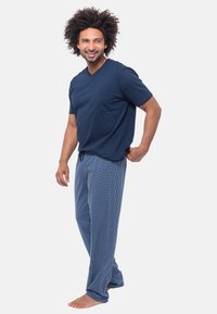 Navy V-Ausschnitt-T-Shirt mit Brusttasche, kombiniert mit blau-weißen karierter Schlafanzughosen, die einen lockeren Schnitt und einen elastischen Bund aufweisen.