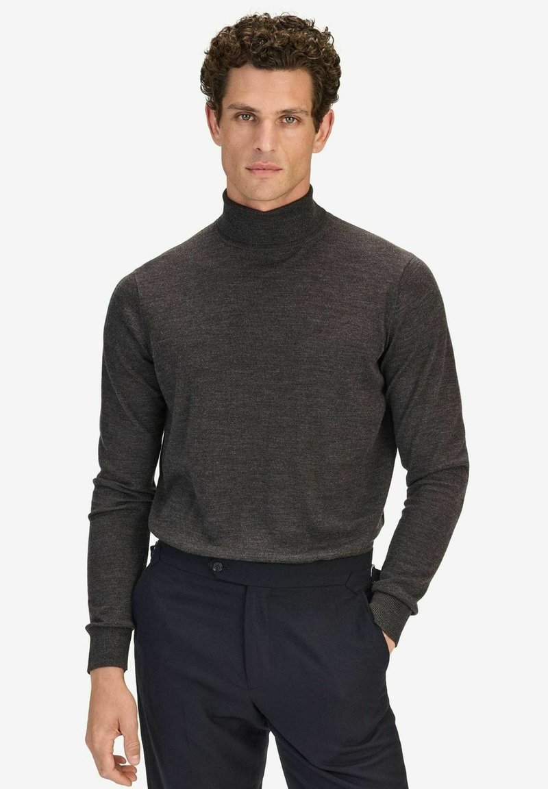 Mörkgrå polotröja i mjukt tyg, med långa ärmar och en åtsittande design. Kombinerad med mörka byxor för kontrast.