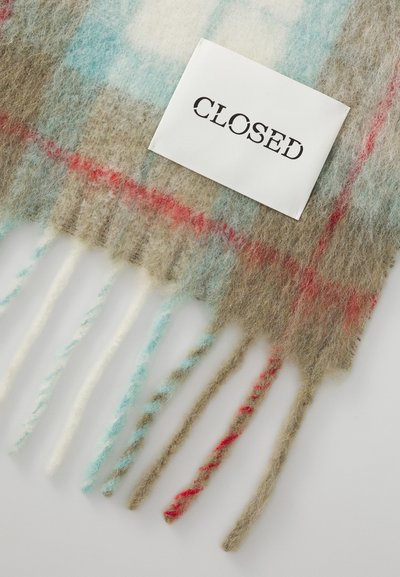 Écharpe en laine avec un motif à carreaux dans des teintes beige, bleu et rouge, avec des extrémités à franges. Une étiquette blanche indique "CLOSED" en texte noir.