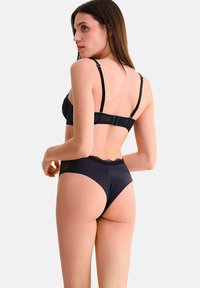 Ensemble de lingerie noir comprenant un soutien-gorge en dentelle transparente avec des bretelles ajustables et une culotte taille haute assortie avec une finition satinée.