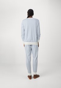 Hellblau gestreiftes Loungewear-Set mit einem langärmligen Oberteil mit Rundhalsausschnitt und passenden Hosen mit elastischen Bündchen und Bund.