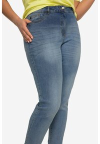 Jeans de mezclilla azul con ajuste slim, lavado desgastado, diseño de cinco bolsillos y cierre frontal con botón. Detalle de costura visible a lo largo de las costuras.