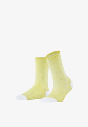 Gelbe Socken mit einem weißen Zickzackmuster, die weiße Akzente an Spitze und Ferse aufweisen. Hergestellt aus weichem, dehnbarem Material mit einem gerippten Bündchen.