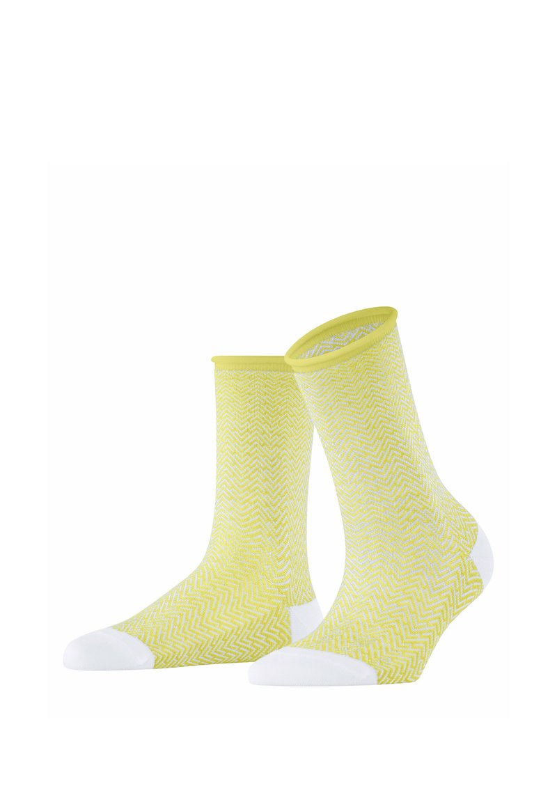 Gelbe Socken mit einem weißen Zickzackmuster, die weiße Akzente an Spitze und Ferse aufweisen. Hergestellt aus weichem, dehnbarem Material mit einem gerippten Bündchen.