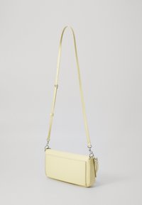 Sac bandoulière en cuir jaune avec une texture lisse, de forme rectangulaire, une bandoulière ajustable et des détails en métal argenté.