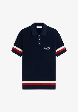 Granatowa koszulka polo z czerwono-białymi paskami na rękawach i obrzeżu, listwa z trzema guzikami oraz białe logo Tommy Hilfiger na piersi.