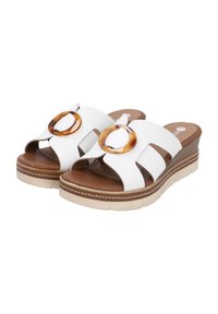 White wedge sandals with two wide straps featuring a circular tortoiseshell accent, brown insole, and contrasting beige outsole.