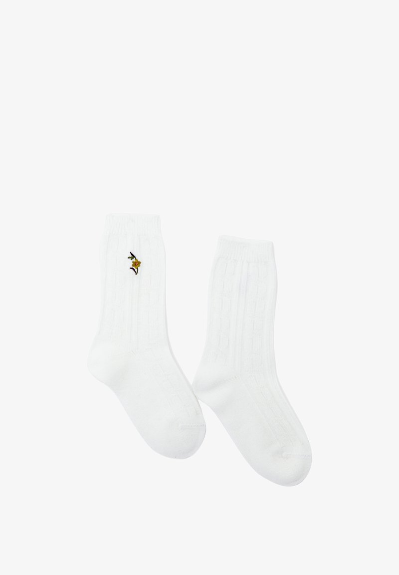 Calzini bianchi in cotone alla caviglia con texture a coste, caratterizzati da un piccolo design di un uccellino ricamato a colori sul lato.
