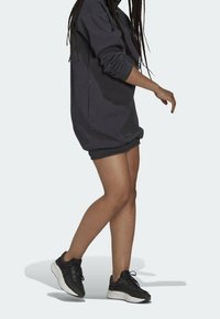 Mörkgrå sweatshirt med långa ärmar, avslappnad passform och ribbad mudd, tillsammans med svarta sportskor och en mörk kort kjol.