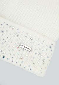 Cappello beanie bianco a maglia con trama a coste, arricchito da dettagli iridescenti sparsi e un'etichetta argentata WITTCHEM sulla visiera.