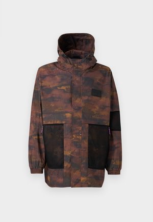 Chaqueta resistente al agua en un patrón de camuflaje marrón y negro. Presenta bolsillos de malla y una capucha con cordón. Ligera con puños elásticos.