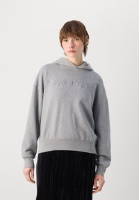 Grå hettegenser med frontlomme, med brodert "Marc O’Polo"-logo, avslappet passform, lange ermer og mykt bomullsmateriale.