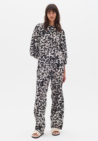 Set de lounge cu model alb-negru, ce include un top lejer cu mâneci largi și pantaloni evazați asortați, confecționat dintr-un material moale.