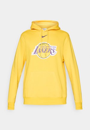 Geltona kapučino striukė su priekiniais kišeniais, su raišteliu reguliuojama gaubtu ir violetiniu "Los Angeles Lakers" logotipo dizainu ant krūtinės. Minkšta audinio tekstūra.