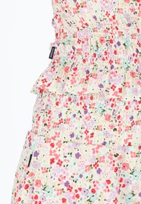 Leichtes Kleid aus floral gemustertem Stoff mit gerafftem Oberteil und Rüschensaum, das pinke, lila und blaue Blumen auf einem cremefarbenen Hintergrund zeigt.