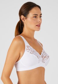 Sostén blanco con detalles de encaje en la parte superior, fabricado en suave algodón, con tirantes ajustables y una banda lisa en la parte inferior para mayor comodidad.
