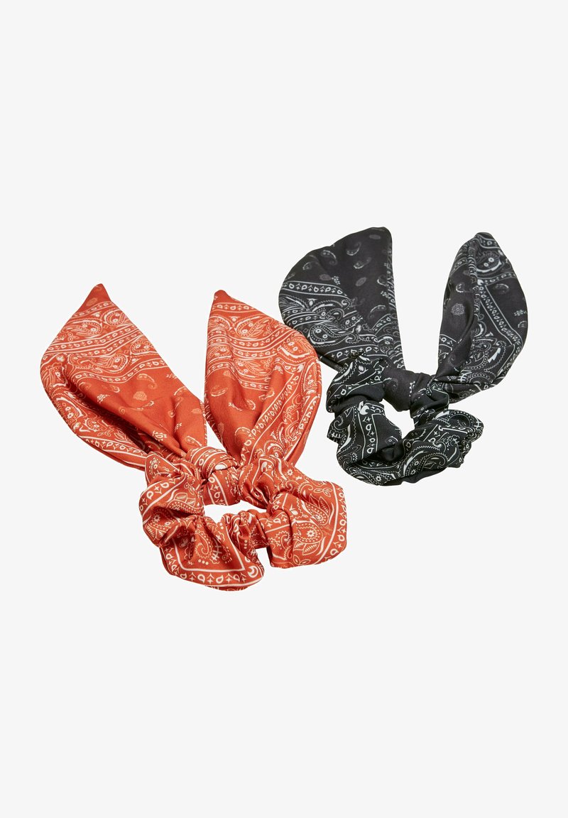 Két bandana mintás hajgumi: az egyik rozsdabarna, fehér paisley mintával, a másik fekete, szintén fehér paisley mintával, puha anyagból, csomózott tetejű.