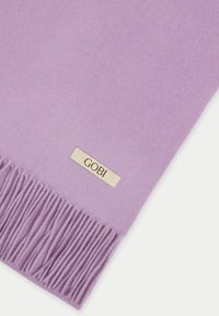 Lavendelullscarf med fransade kanter, försedd med en liten guldetikett med "GOBI." Tyget har en jämn textur.