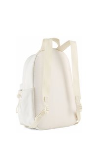 Sac à dos en tissu blanc avec une forme arrondie, des bretelles ajustables et une poche latérale, présentant une texture lisse et un design minimaliste.