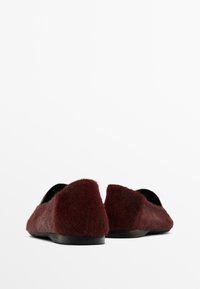 Ballerine borgogna con una morbida texture pelosa e un design a punta tonda. Fodera interna nera e suola nera minimalista. Nessun hardware visibile.