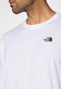 Λευκό βαμβακερό t-shirt με στρογγυλή λαιμόκοψη, μ ε μικρό μαύρο κεντητό λογότυπο της «The North Face» στο αριστερό στήθος.