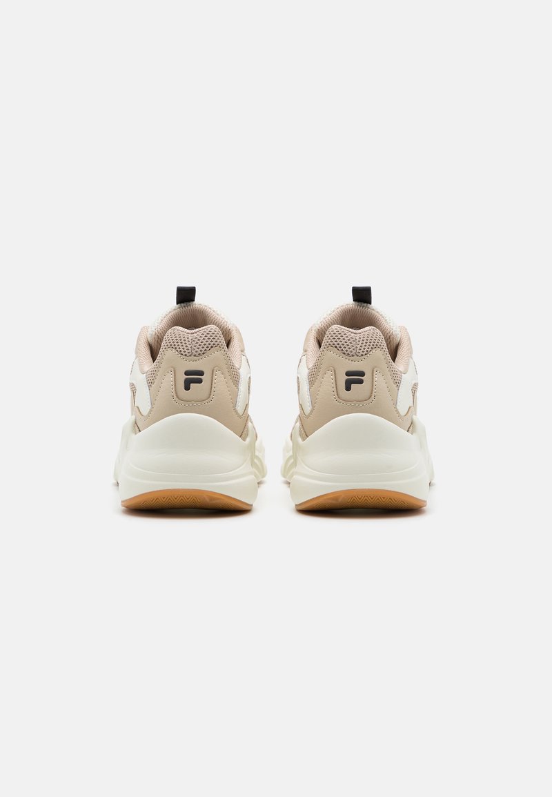 Zapatillas deportivas beige con parte superior de malla texturizada, acentos blancos y suela de goma. Presentan un tirador negro en el talón y un logo sutil.