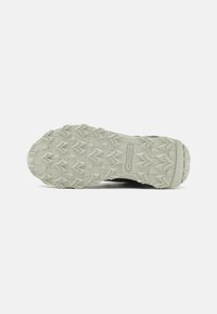 Schwarze Sport Schuhsohle mit einer strukturierten, hellgrauen Gummi-Außensohle und multidirektionalen Stollen für Traktion und Stabilität.