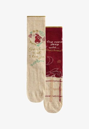 Kniestrümpfe in Beige und Rot. Die beigefarbenen Socken zeigen eine Hasen-Grafik und Text, während die roten Socken ein Sternenmuster und Feiertagstext haben. Mit goldenen Akzenten.