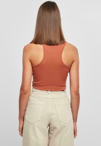 Brun strikket crop tank top kombinert med lysebeige høy midje vide bukser, med store baklommer og en teksturert overflate.