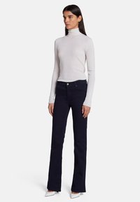 Valkoinen ribattu kauluspaidat yhdistetty tummansinisiin leveälahkeisiin farkkuihin, joissa on etupainike ja taskudetaljot. Slim fit. Valkoiset kärjetossut.