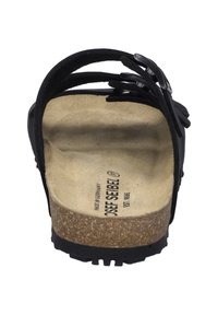 Black leather sandal with cork footbed, open back design, and curved straps featuring cut-out details. Rubber sole for traction.