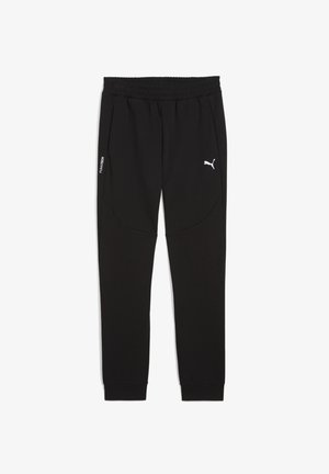 Pantalons de survêtement noirs en tissu doux, avec une taille élastique, des poches latérales et un logo Puma blanc sur la cuisse gauche.
