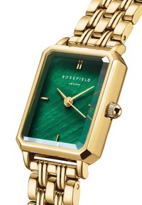 Reloj rectangular dorado con una esfera texturizada verde, manecillas doradas y cristal de aumento, que presenta una pulsera de eslabones de metal dorado.