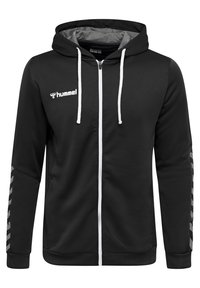 Sweat à capuche noir avec fermeture éclair blanche, cordons de serrage blancs, logo "hummel" sur la poitrine, et motif en chevrons sur les manches inférieures.
