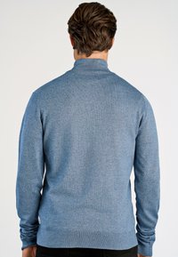 Blauw gebreid sweater met een hoge kraag, aansluitend ontwerp, lange mouwen en geribde manchetten. Materiaal lijkt op wol met een gestructureerde afwerking.