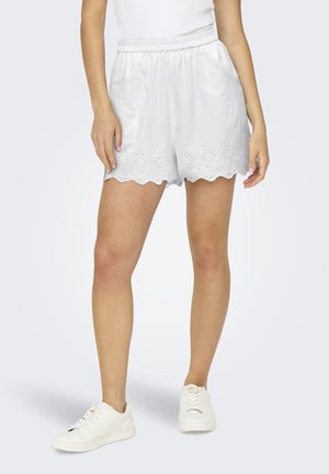 Shorts bianchi con orlo a scalloped e dettagli floreali intagliati, realizzati in un tessuto liscio. Abbinati a sneakers bianche. Vita elasticizzata.
