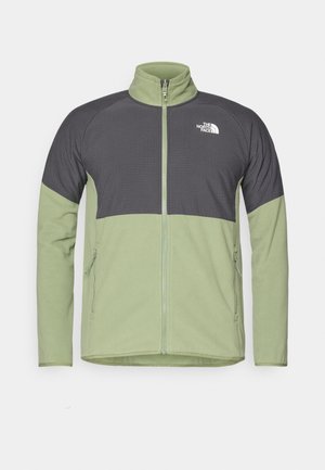 Fleece jacket in olive green and dark gray. Full zip, high collar, with two side pockets and textured upper panel. Features logo on chest.