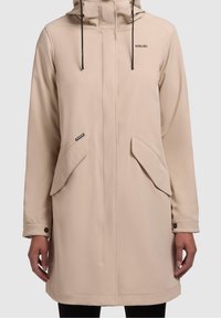 Manteau imperméable beige clair avec capuche, doté de deux poches avant, d'un cordon noir et d'un logo sur la poitrine. Texture lisse.