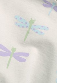 Un tessuto leggero presenta un motivo ripetuto di libellule in verde pallido, blu con pois e lavanda su uno sfondo bianco.