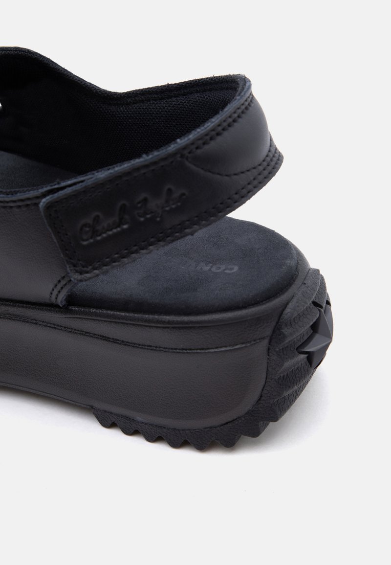 Schwarze Plateau-Sandale mit verstellbarem Riemen und geprägtem Logo, dicker gepolsterter Sohle und profilierter Außensohle mit Stern-Detail.