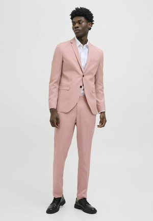 Lichtroest pak gemaakt van een gladde stof, met een enkelknopssluiting jack en slim-fit broeken, gecombineerd met een wit skjort en zwarte schoenen.