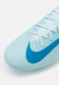 Jasnoniebieski but piłkarski Nike o teksturowanej cholewce, z dużym niebieskim logo Swoosh i białymi sznurowadłami na górze.