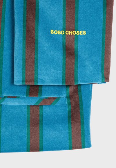 Plava tkanina s smešnim i zelenim vertikalnim prugama; "BOBO CHOSES" izvezeno u žuto; glatka tekstura.