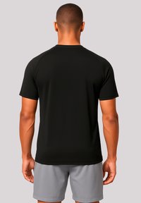 Black athletic t-shirt with short sleeves, smooth texture, round neckline, and raglan shoulder seams. Worn with gray shorts.