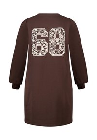 Bruine jurk met lange mouwen, met een wit bloemmotief op de achterkant en het nummer "68" erboven gedrukt. Zachte stof, ontspannen pasvorm.