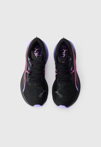 Une paire de chaussures de sport noires avec des accents violets et roses, des lacets noirs et un dessus en mesh texturé, vue de dessus sur un fond blanc.