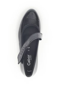 Chaussure plate en cuir verni noir avec un bout rond et une sangle réglable. Surface texturée et semelle intérieure rembourrée pour plus de confort.