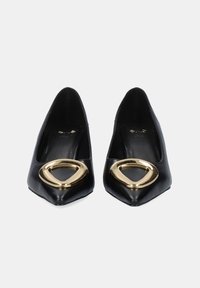 Zapatos de tacón de punta negra de cuero con un acento circular dorado en la parte superior. Textura suave con un diseño refinado y minimalista.