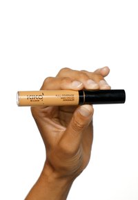 Kiko Milano full coverage concealer for mørke ringer i en gjennomsiktig tube med sort lokk, som viser en beigefarget væske innvendig.