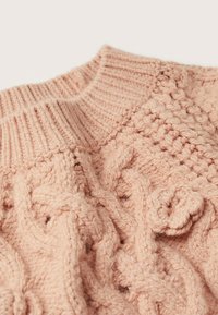 Pull en maille torsadée rose pâle. Il présente un col côtelé et des motifs texturés, avec un design torsadé proéminent sur l'ensemble.